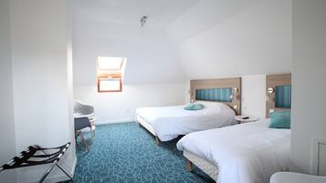 A hotel room with two beds, a desk, a chair, and a small window.