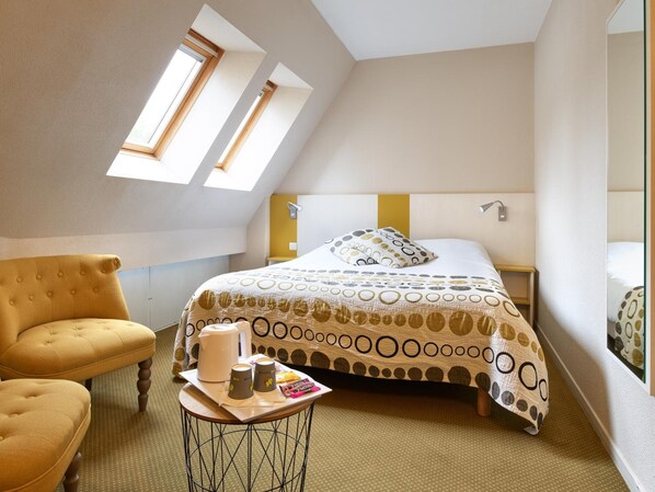 A cozy room with a bed, a chair, and a small table with a tray of items.