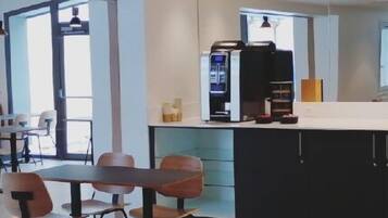 A modern cafe with a counter, seating area, and a coffee machine.