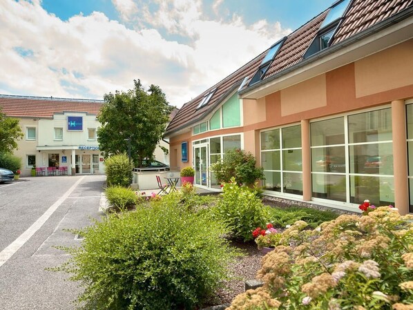 A hotel with a reception area, large windows, and a parking lot.