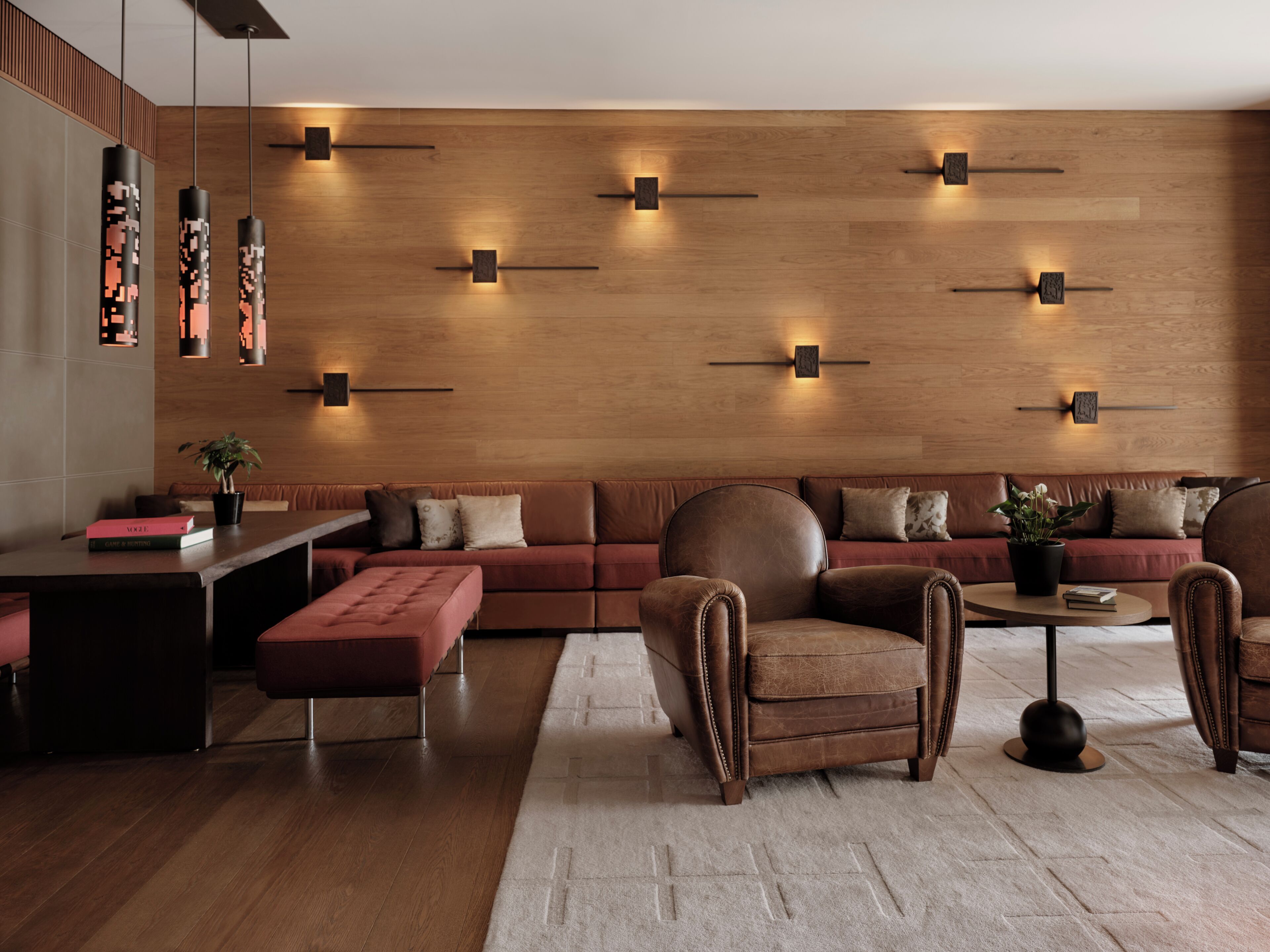 Una sala de estar moderna con un sofá modular, un sillón de cuero, una mesa de centro e iluminación empotrada en la pared.