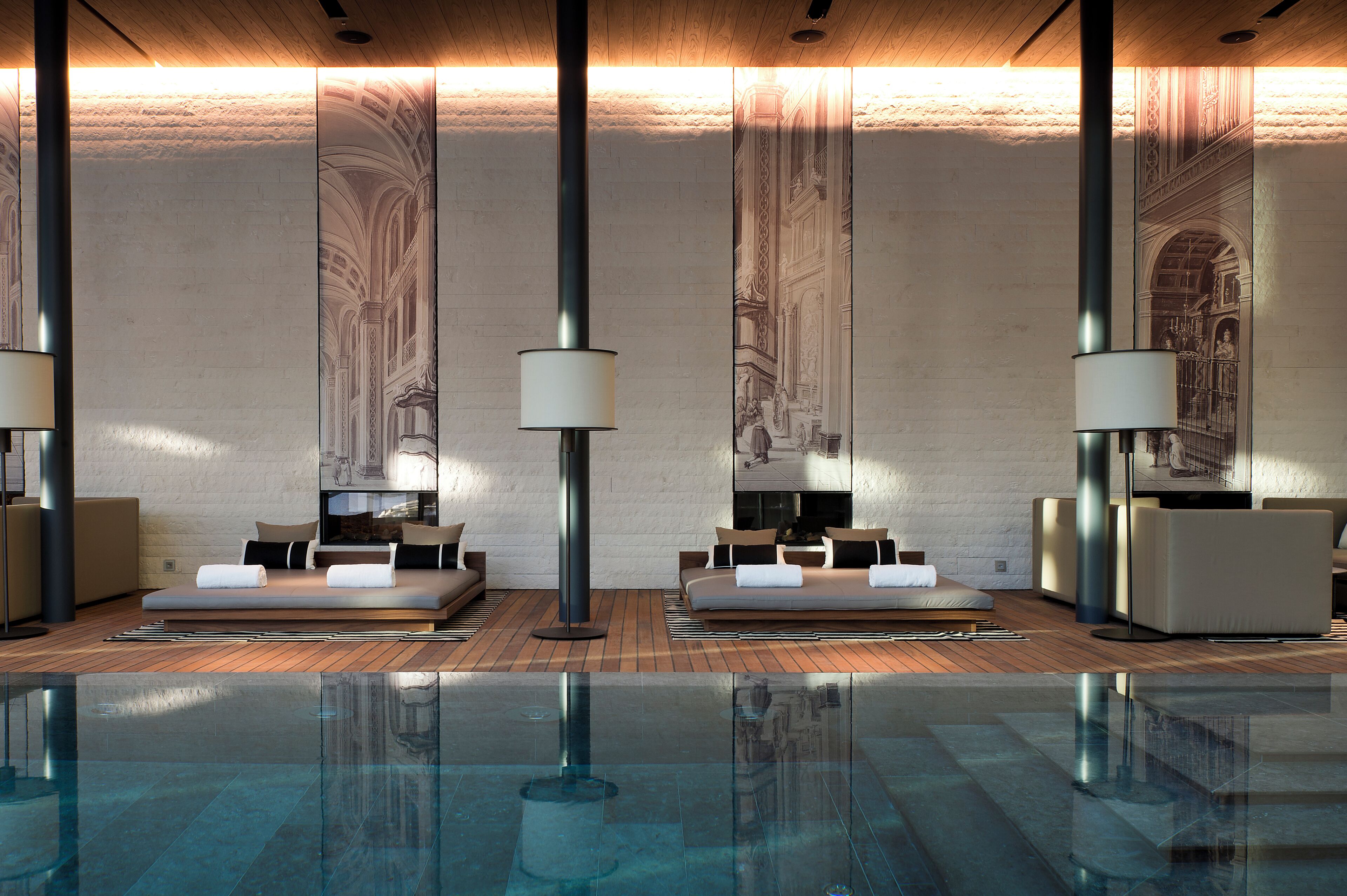 A modern spa area with two seating areas, a large reflective pool, and high ceilings with decorative wall panels.