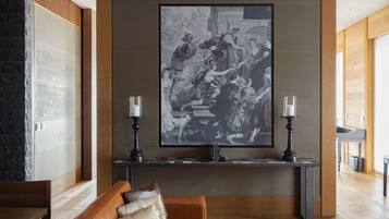 A modern lobby with a large black and white painting, a wooden bench, and a console table with two candles.