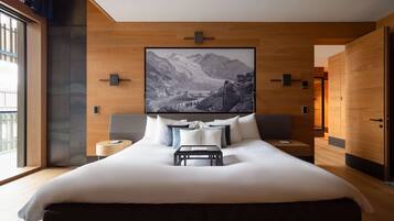 Une chambre d’hôtel moderne avec un grand lit, des panneaux de bois, un tableau représentant un paysage de montagne et une vue sur l’extérieur.