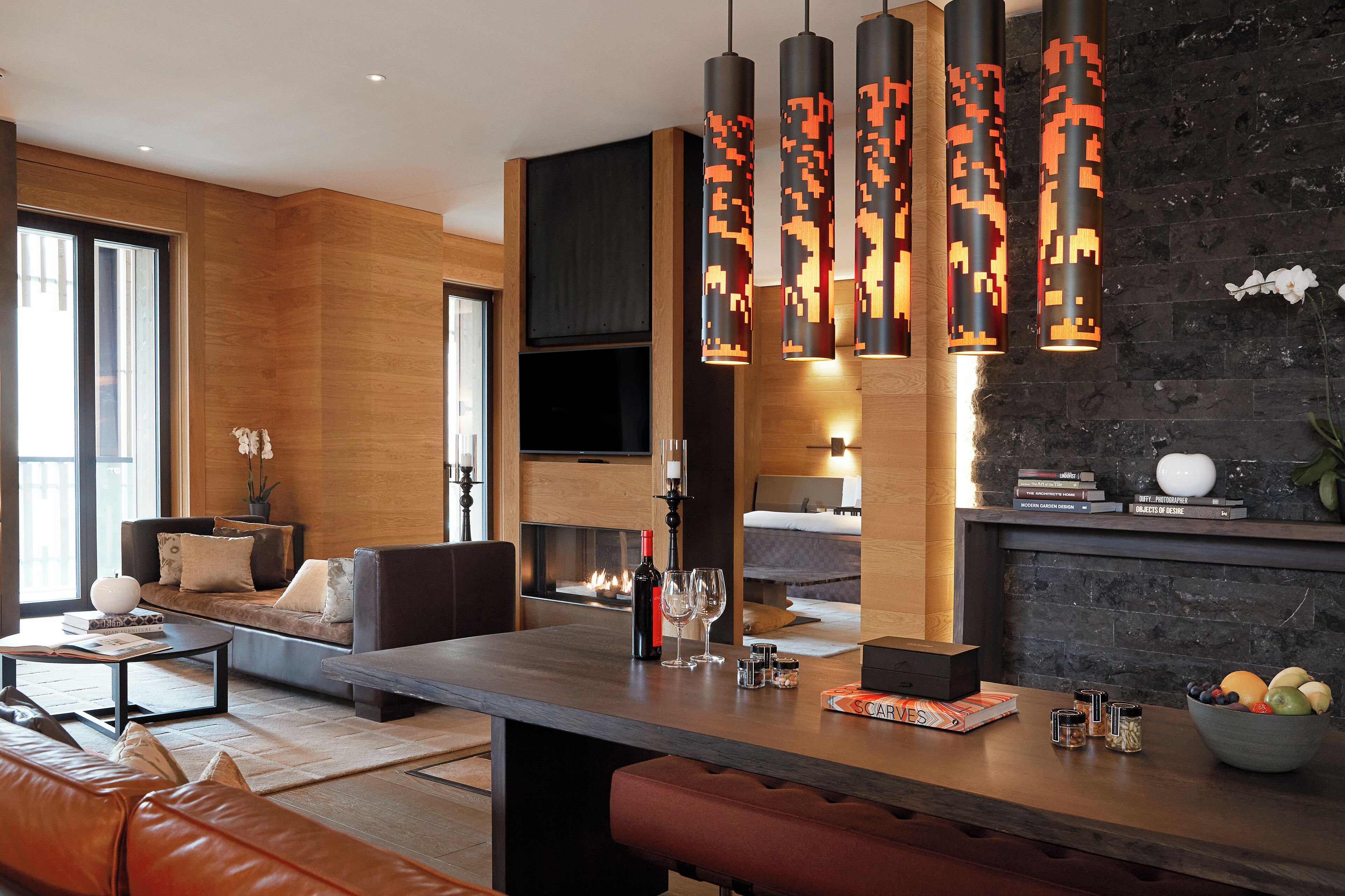 A modern living room with a sofa, coffee table, and a fireplace. There are hanging pixel-patterned lights above the fireplace.