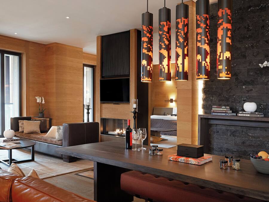 A modern living room with a sofa, coffee table, and a fireplace. There are hanging pixel-patterned lights above the fireplace.