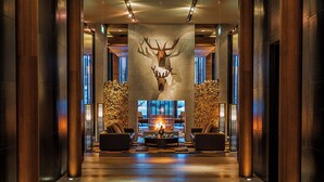 A lobby with a large deer head sculpture, a fireplace, and two sofas. - The Chedi Andermatt (Andermatt)