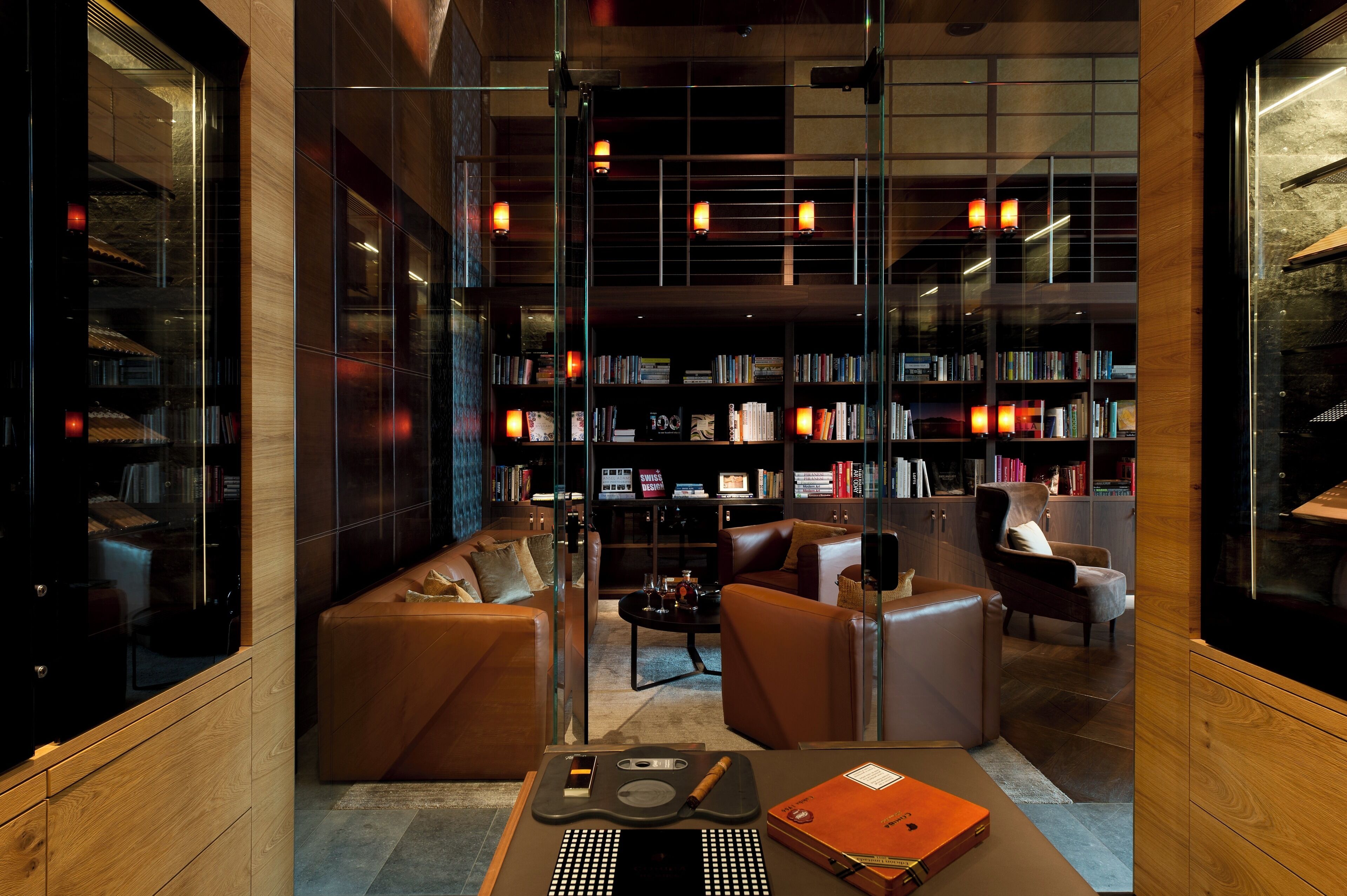 Eine moderne Bibliothek mit Ledersofas, einem Couchtisch und Bücherregalen voller Bücher.