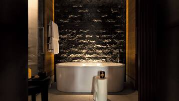 A modern bathroom with a freestanding bathtub, a towel rack, and a small table with a candle.