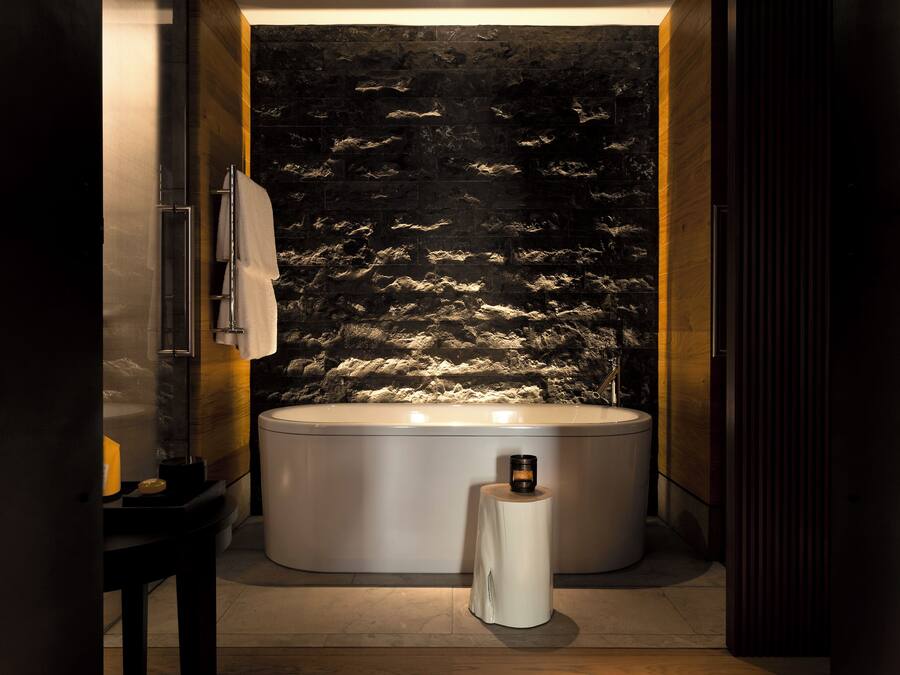 A modern bathroom with a freestanding bathtub, a towel rack, and a small table with a candle.