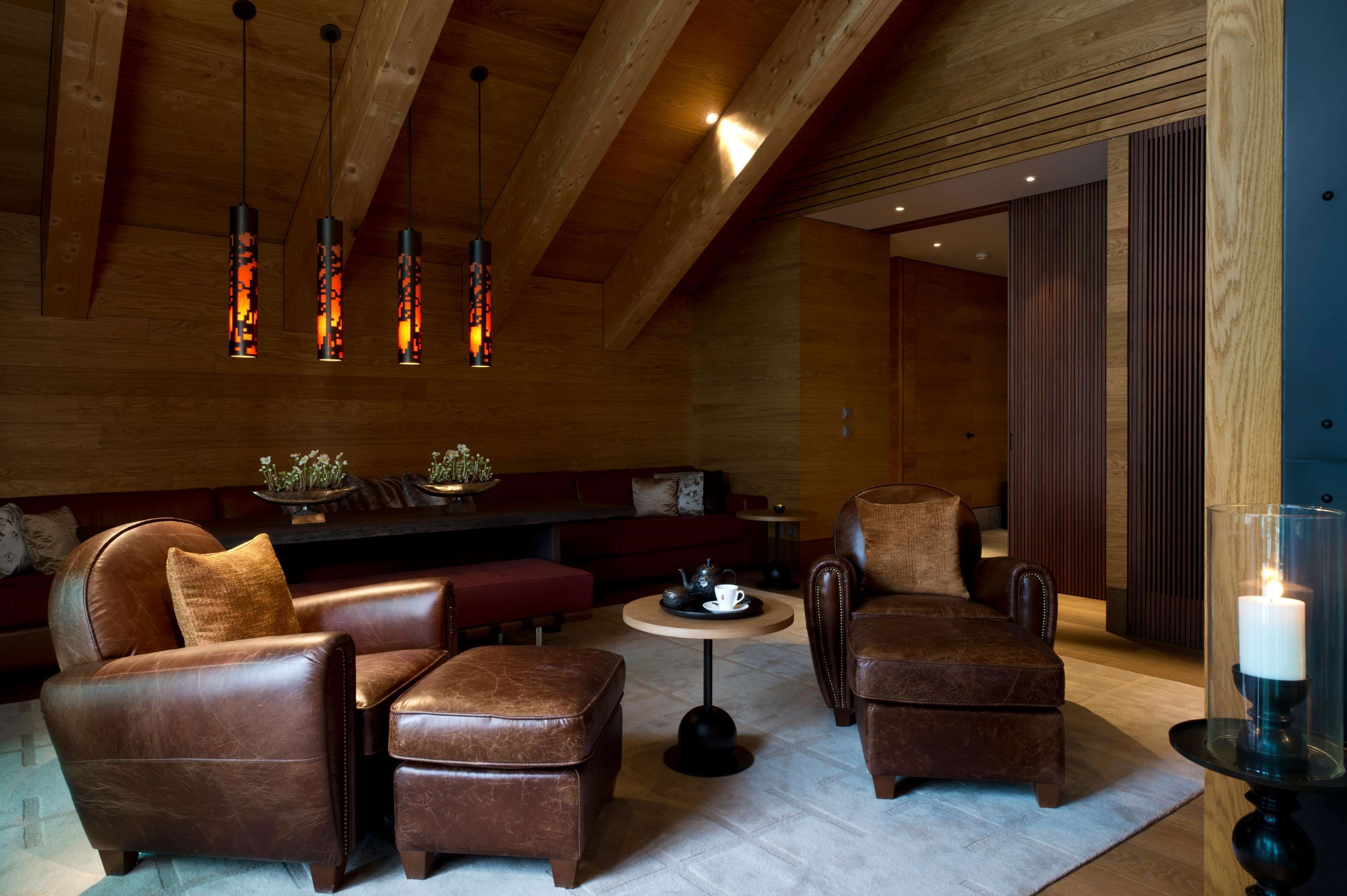 A cozy lounge area with leather sofas, a round coffee table, and pendant lighting.
