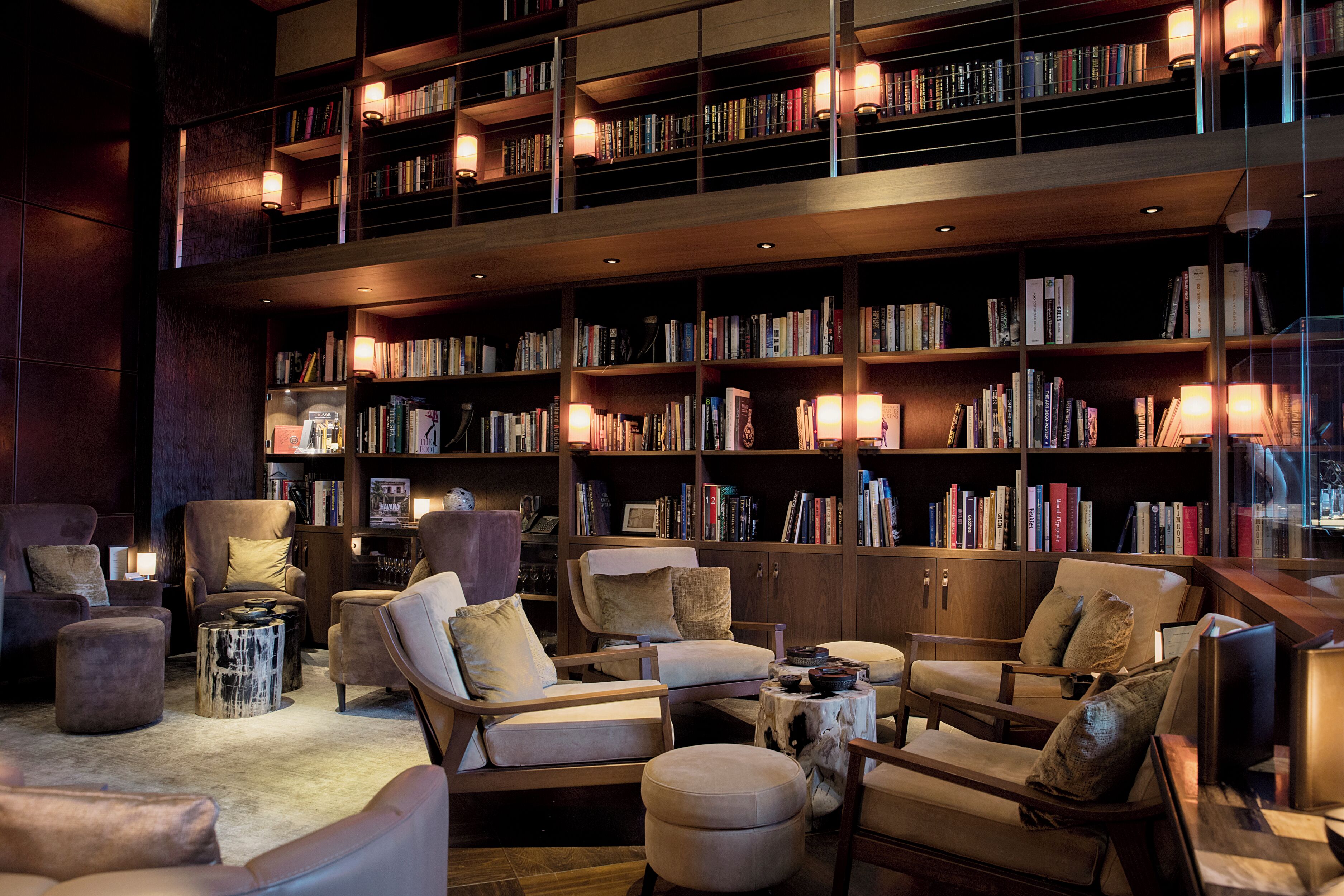 A library with multiple bookshelves, comfortable seating, and reading lamps.