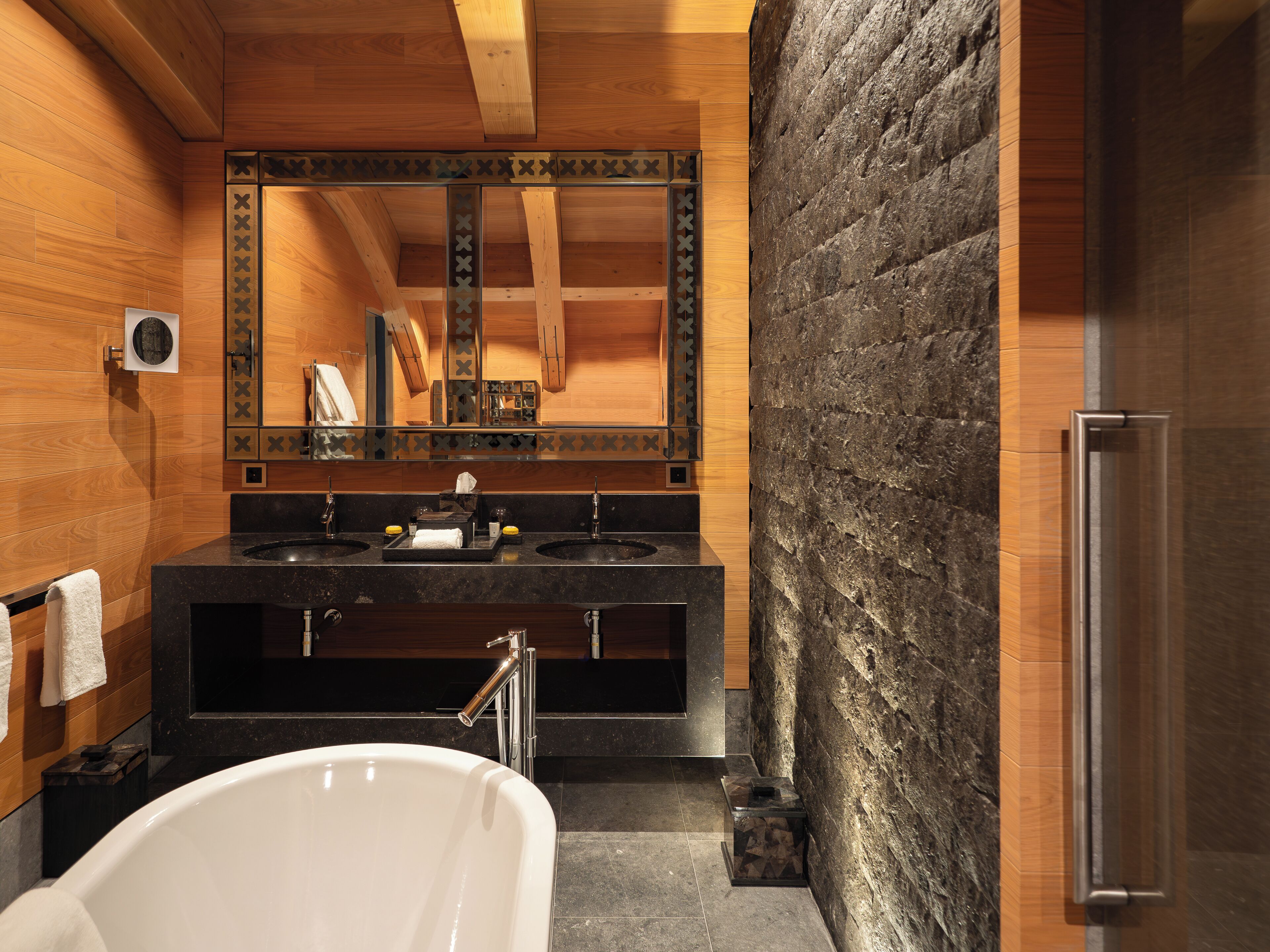Un baño moderno con una bañera independiente, dos lavamanos y un espejo grande.