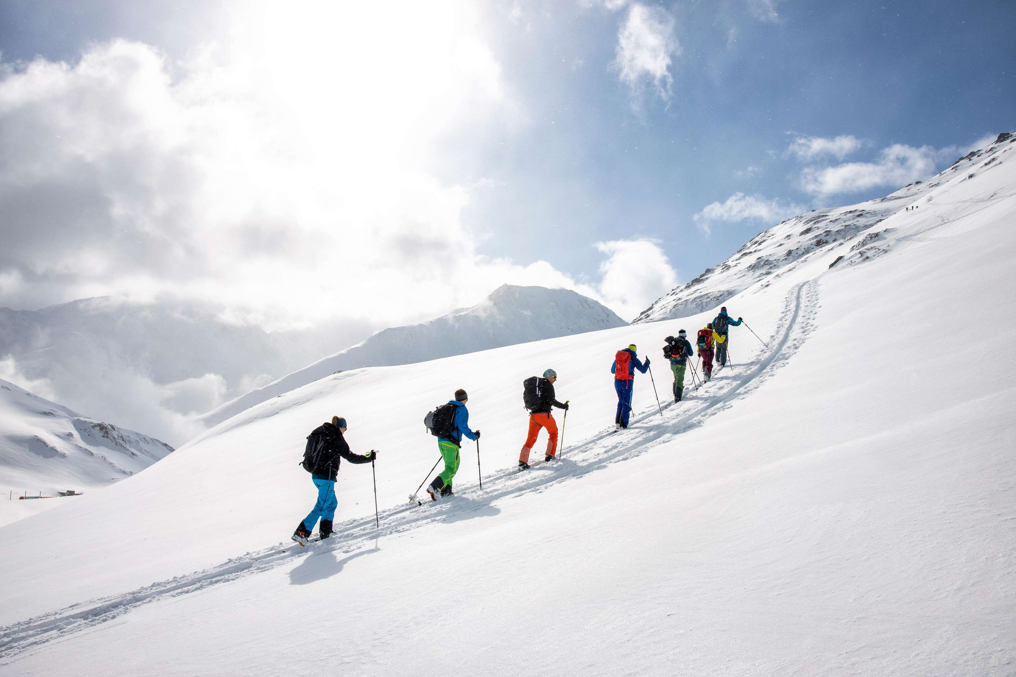 Un groupe de personnes qui fait de la randonnée sur un sentier de montagne enneigé.