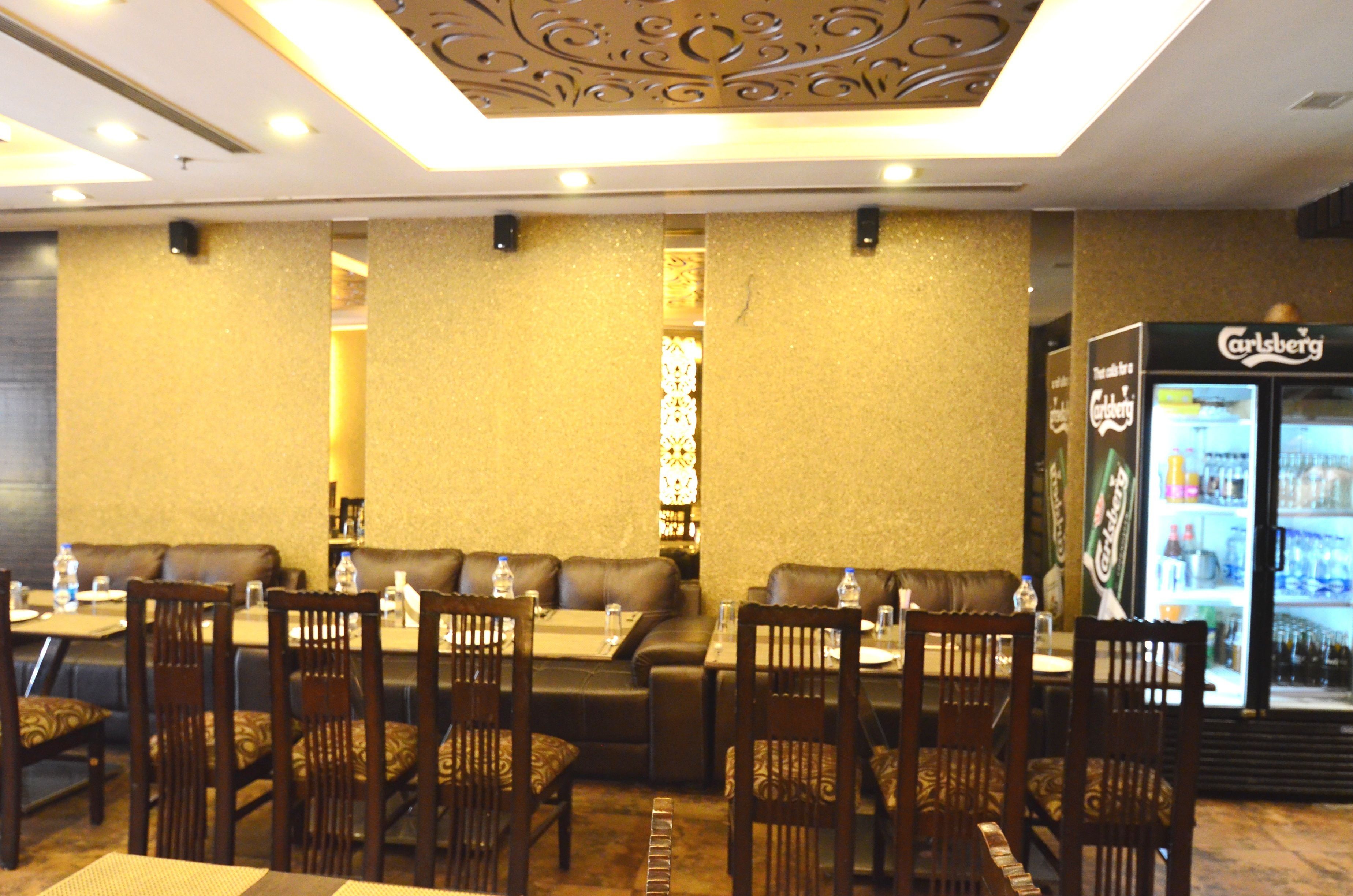 A restaurant with booths and tables, a Carlsberg refrigerator, and a decorative ceiling.