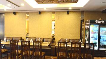 A restaurant with booths and tables, a Carlsberg refrigerator, and a decorative ceiling.