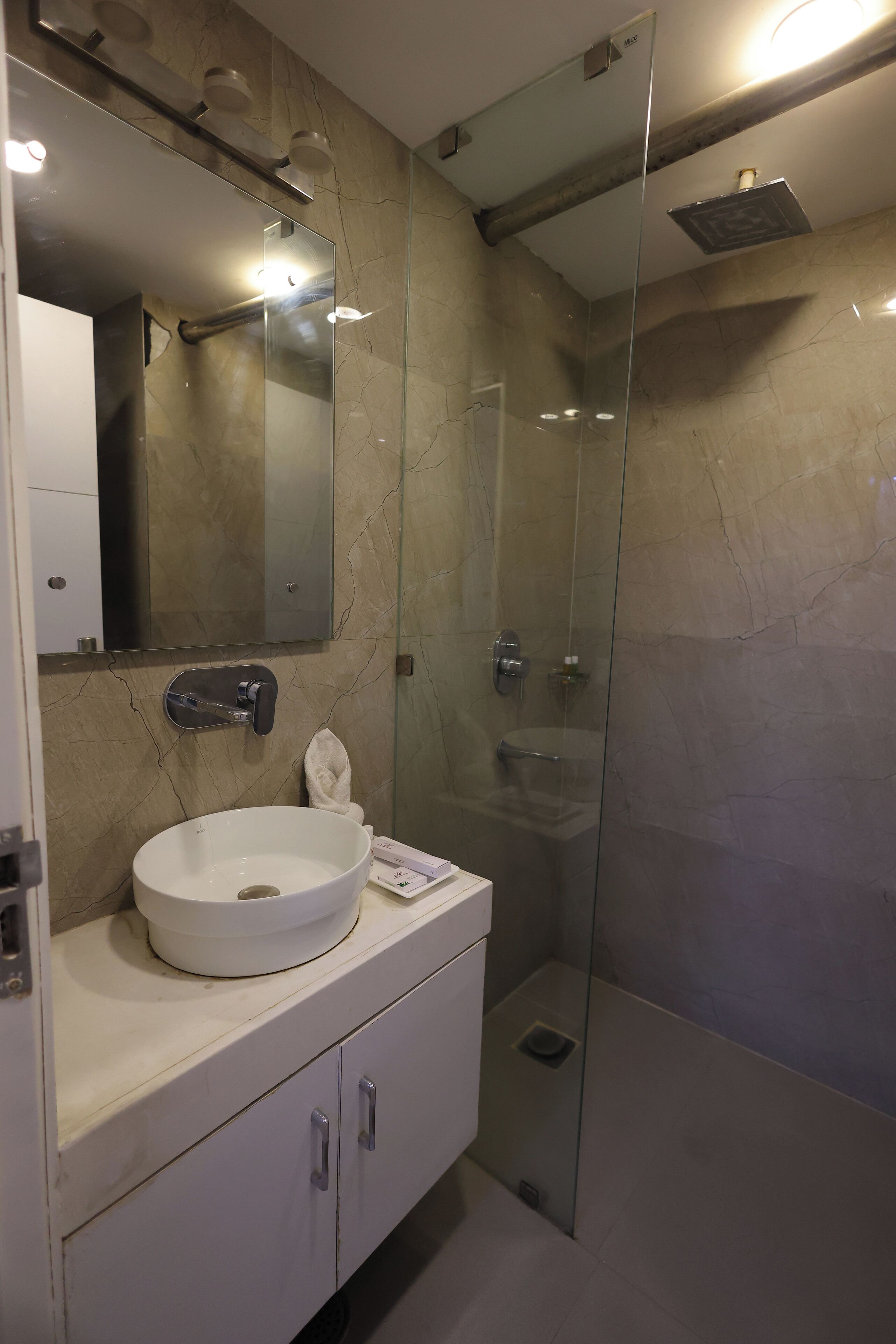A modern bathroom with a glass-enclosed shower, a white sink, and a large mirror.