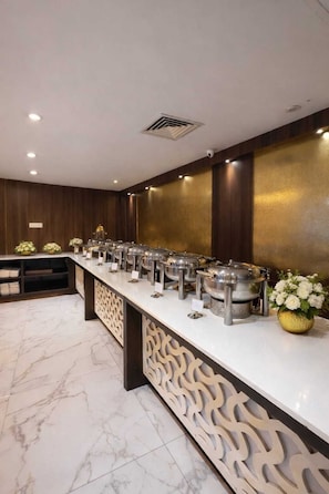 A hotel reception area with a marble floor, a reception desk, and a buffet line with multiple food stations. - Hotel Ramhan Palace (New Delhi)