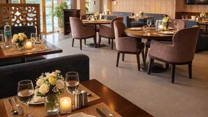 Un comedor moderno con mesas dispuestas para dos, con velas y centros de mesa florales.