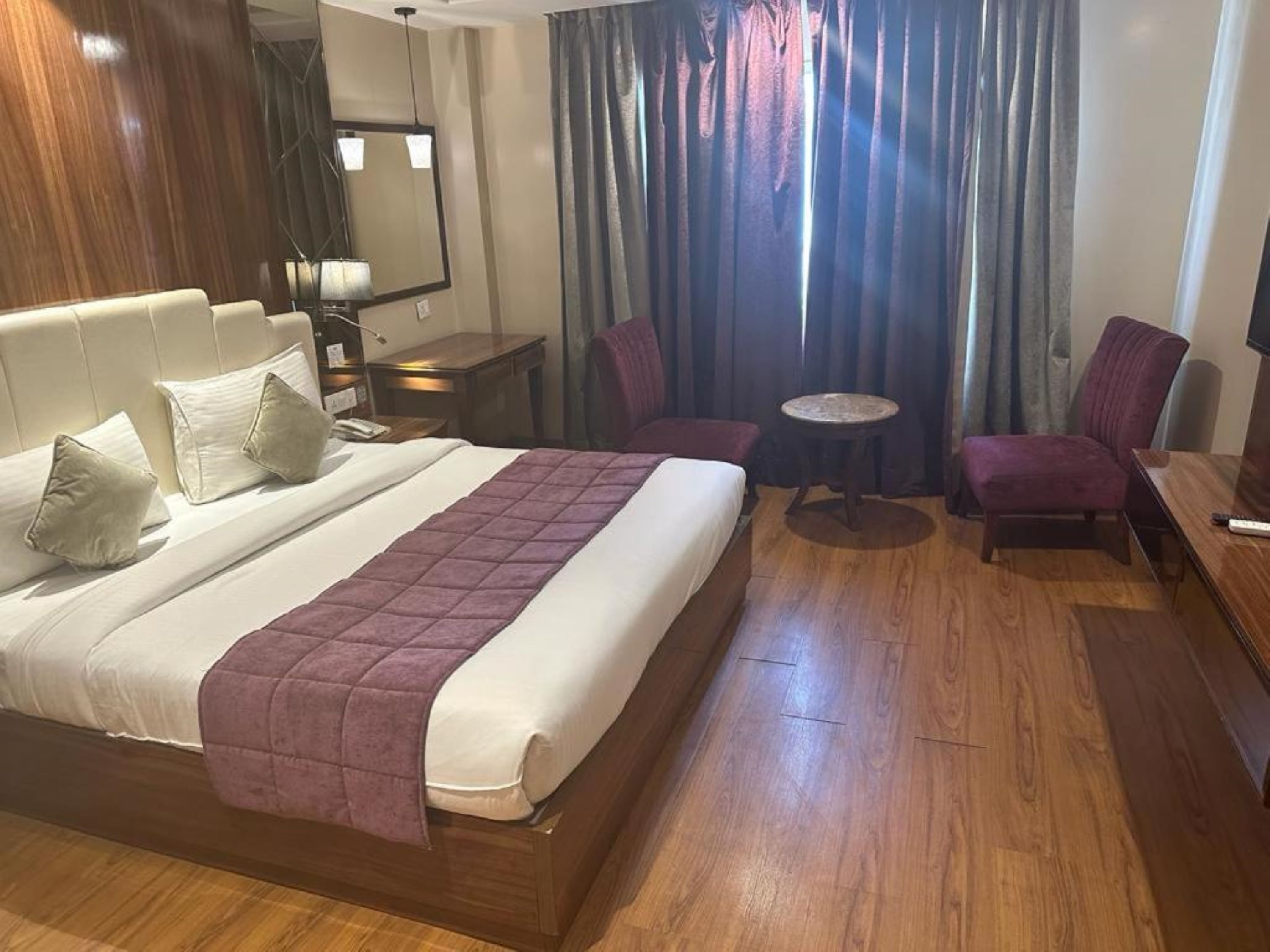 Ein Hotelzimmer mit einem großen Bett, einem Schreibtisch, einem Stuhl, einem kleinen Tisch und einem Fernseher.