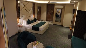 Una habitación de hotel con una cama, dos sillones, una mesita redonda y un espejo.