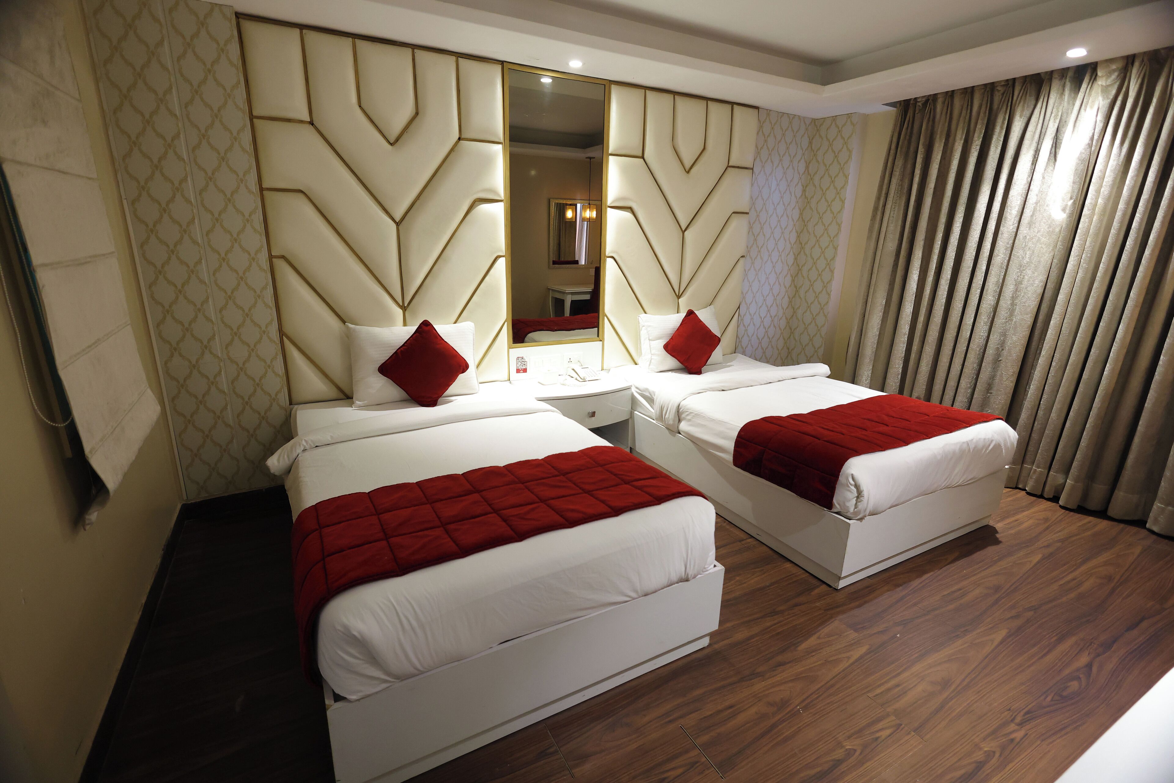 Habitación de hotel con dos camas, un espejo grande y un diseño moderno.