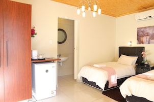 Un dormitorio con dos camas, un refrigerador pequeño, un lavabo y un armario de madera.