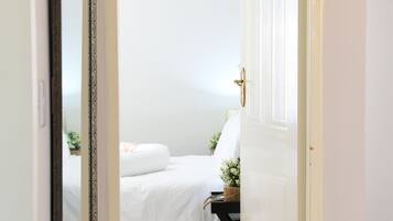 A bedroom with a bed, a bedside table with a plant, and a door.