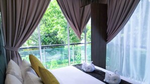 Un dormitorio con un ventanal grande, ropa de cama blanca y una almohada amarilla.