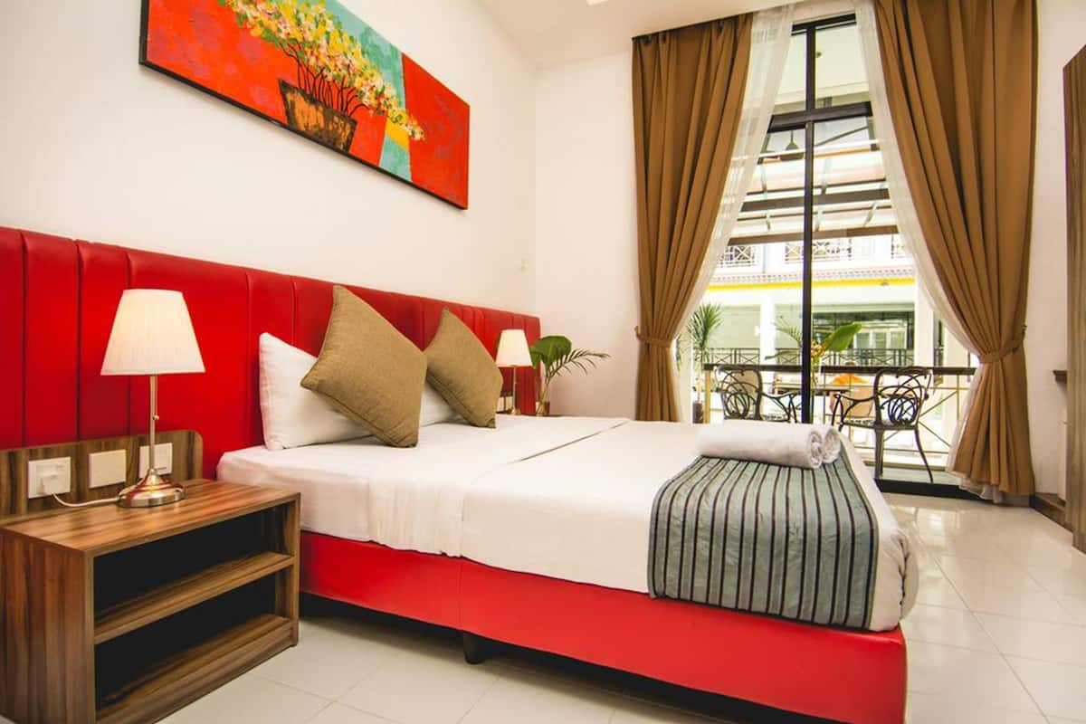A hotel room with a red upholstered headboard, a white bedspread, and a view of the outside through large windows.