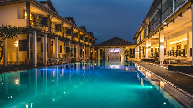 Un hotel con piscina, mobiliario exterior y un cartel que dice "ALIA Resort".