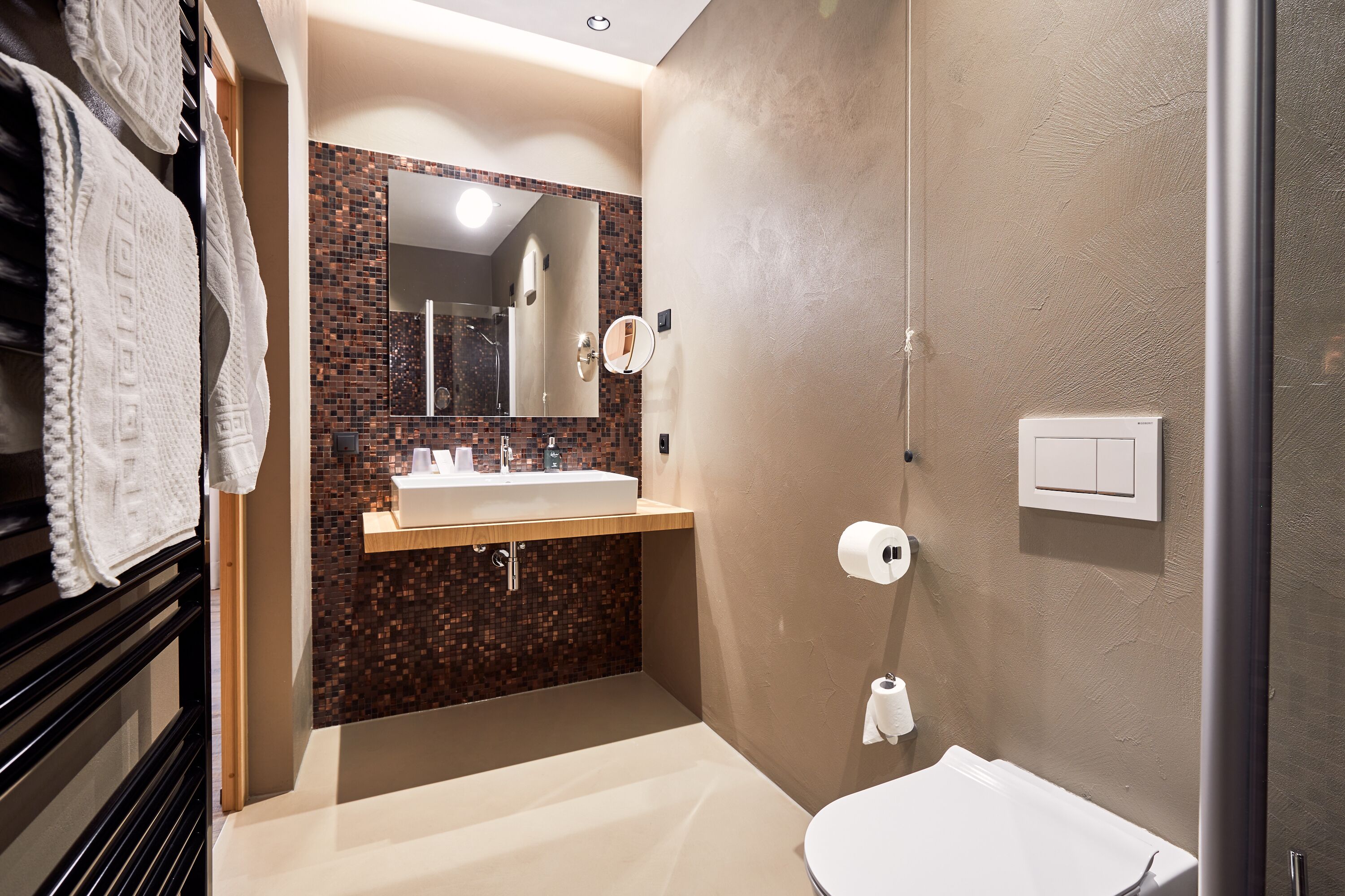 A modern bathroom with a sink, mirror, and toilet.