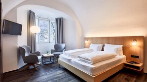 A modern hotel room with a wooden bed, a desk, a chair, and a TV mounted on the wall. - Walther von der Vogelweide (Chiusa)
