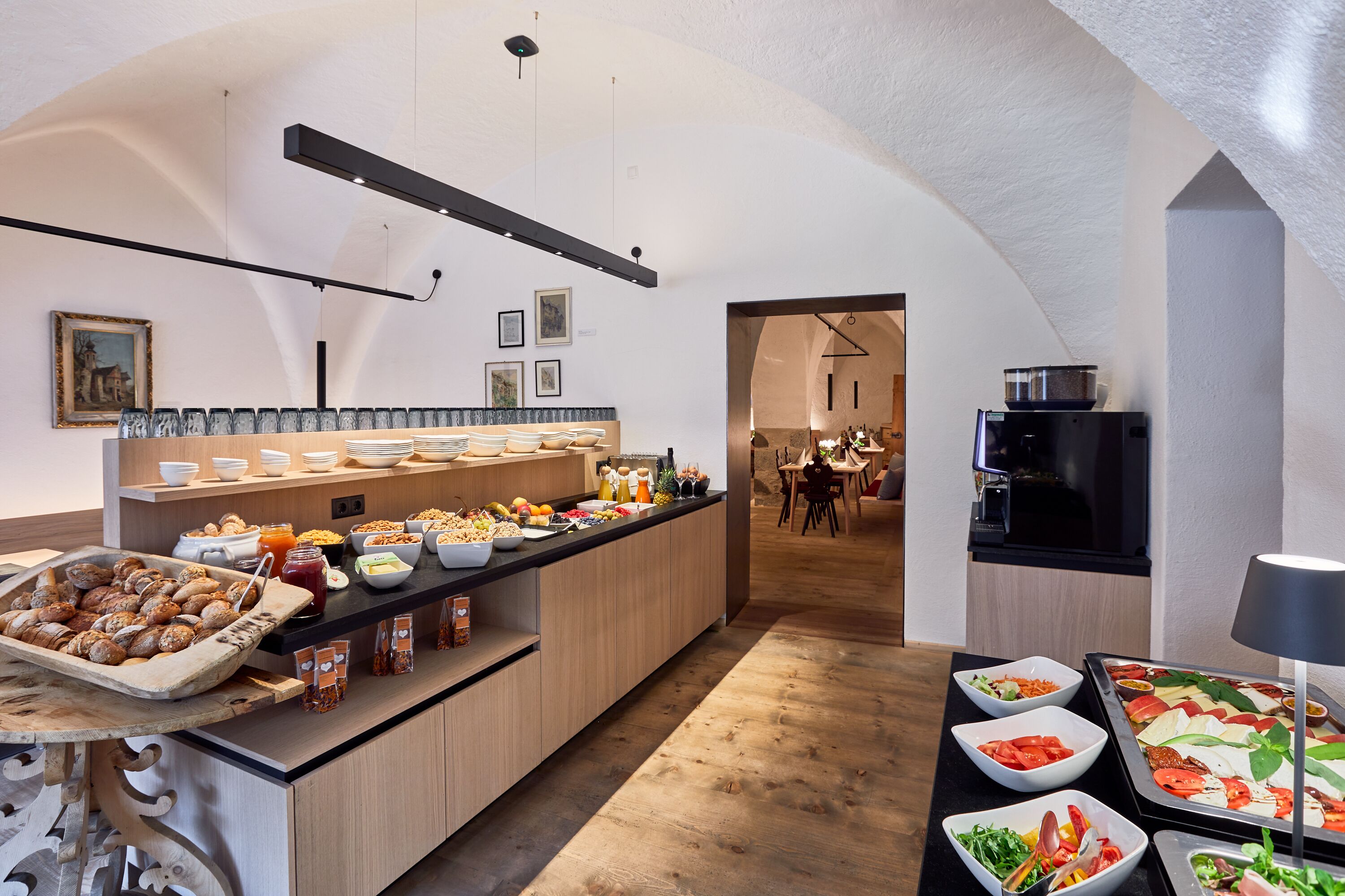 A breakfast buffet with various food items and a kitchen area in the background.