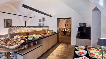 A breakfast buffet with various food items and a kitchen area in the background.