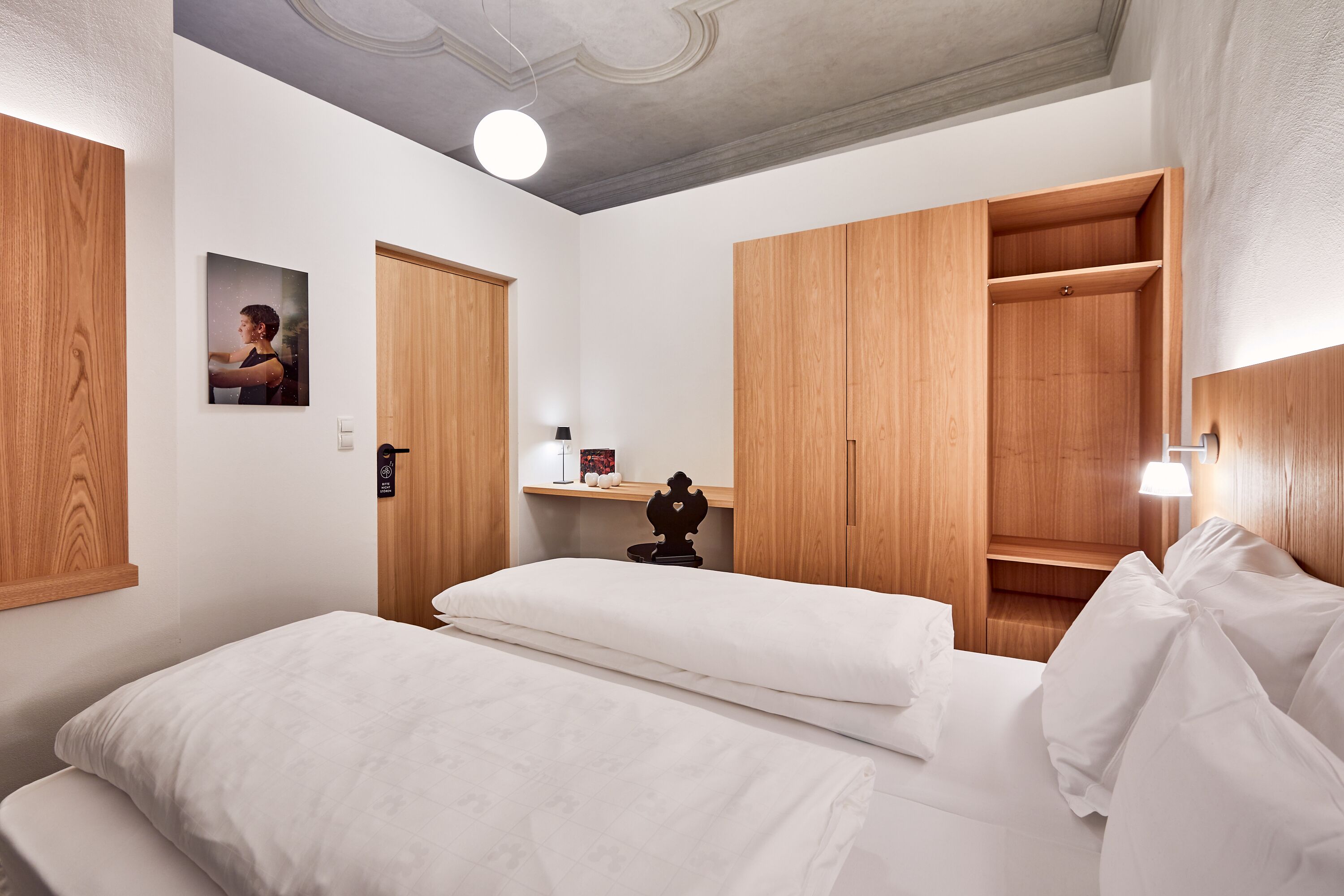 Un dormitorio con una cama, un armario de madera y una mesita de noche con una lámpara.