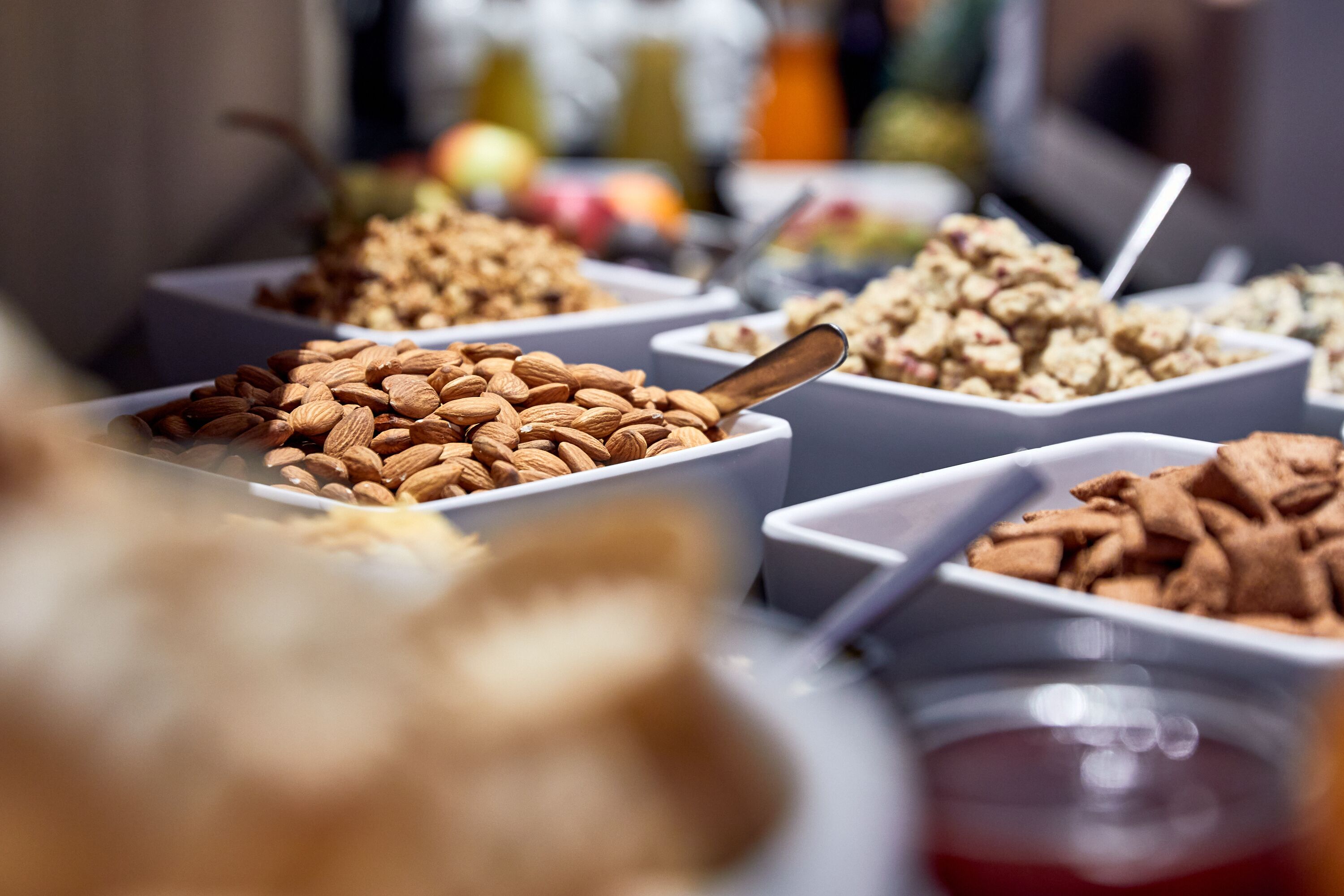 Variedad de alimentos en recipientes, como almendras y otros bocadillos.