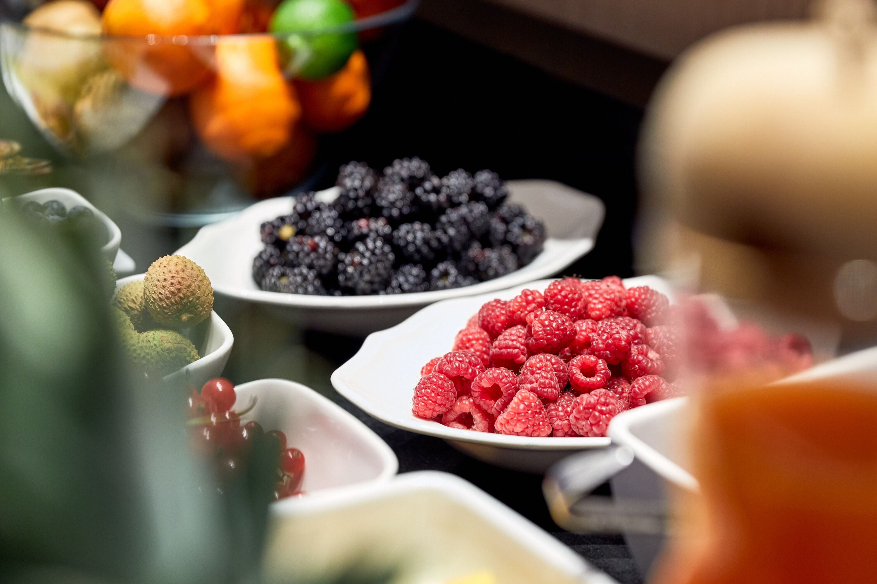 A variety of fruits including raspberries, blackberries, and kiwis on a buffet table.