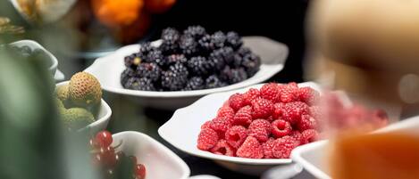 A variety of fruits including raspberries, blackberries, and kiwis on a buffet table.