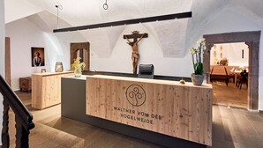 A reception desk with a wooden finish and a crucifix on the wall. - Walther von der Vogelweide (Chiusa)