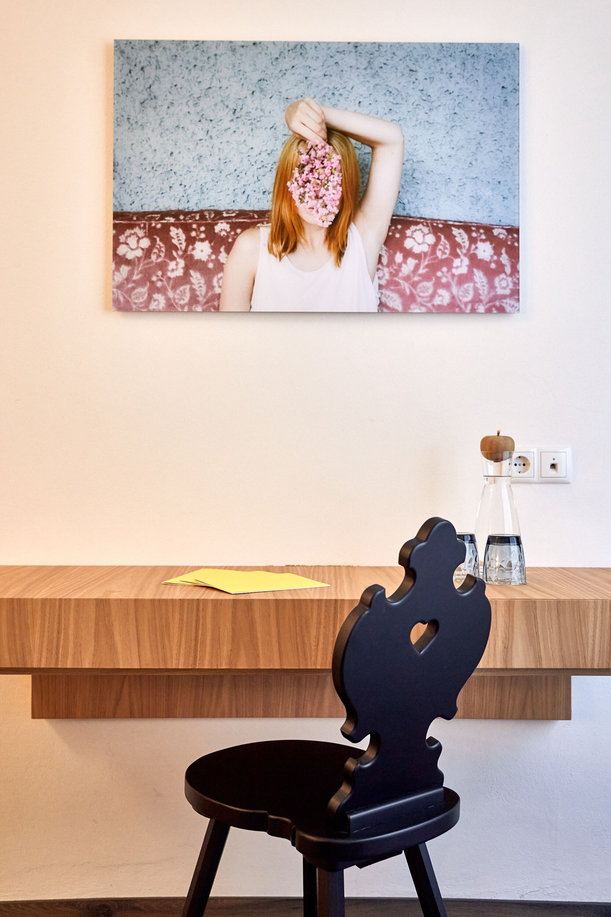 Un interior moderno con un escritorio de madera, una silla negra y una obra de arte colgada en la pared.
