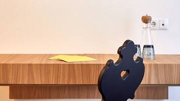 Un interior moderno con un escritorio de madera, una silla negra y una obra de arte colgada en la pared.