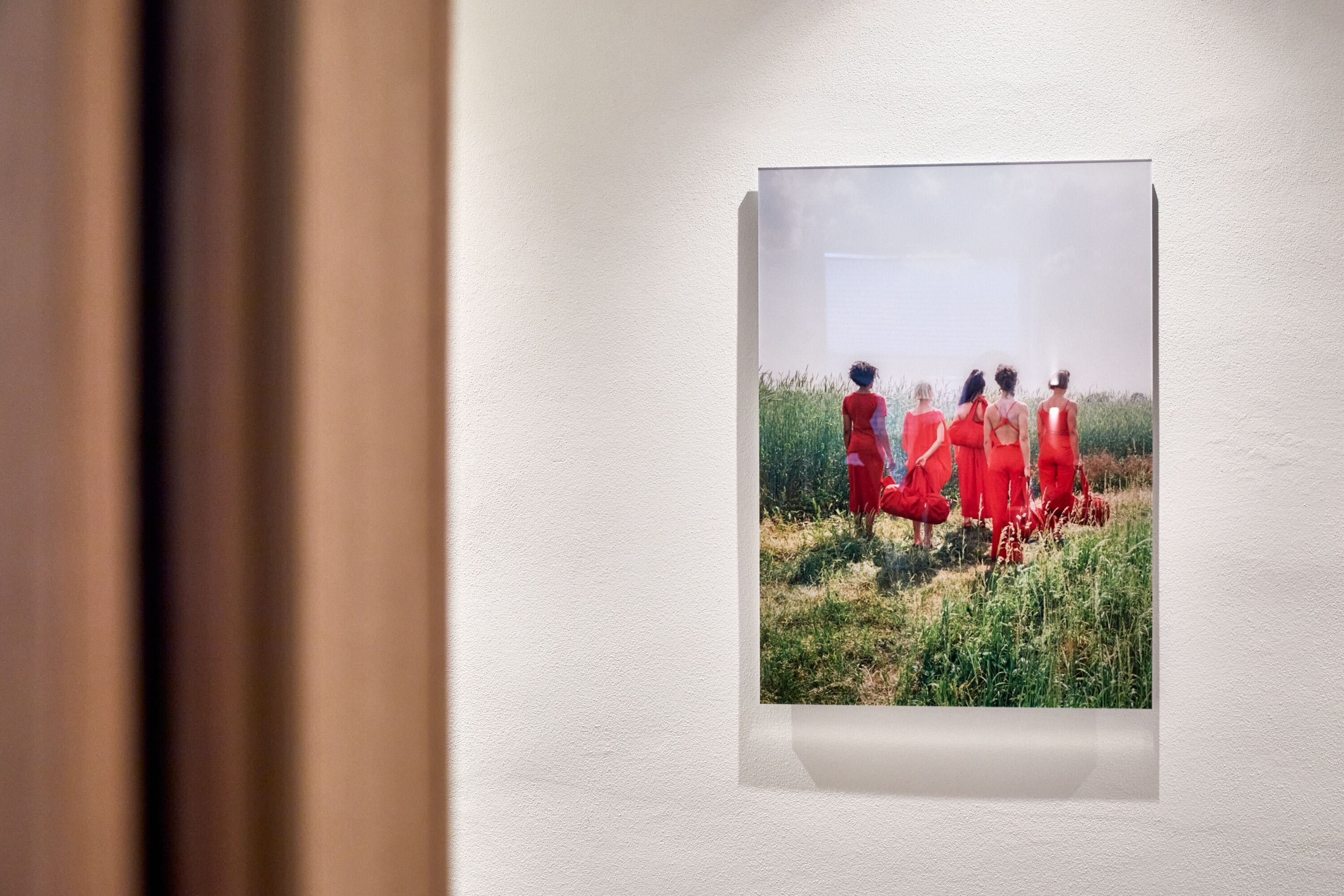 A framed photograph of a group of people in red dresses standing in a field.