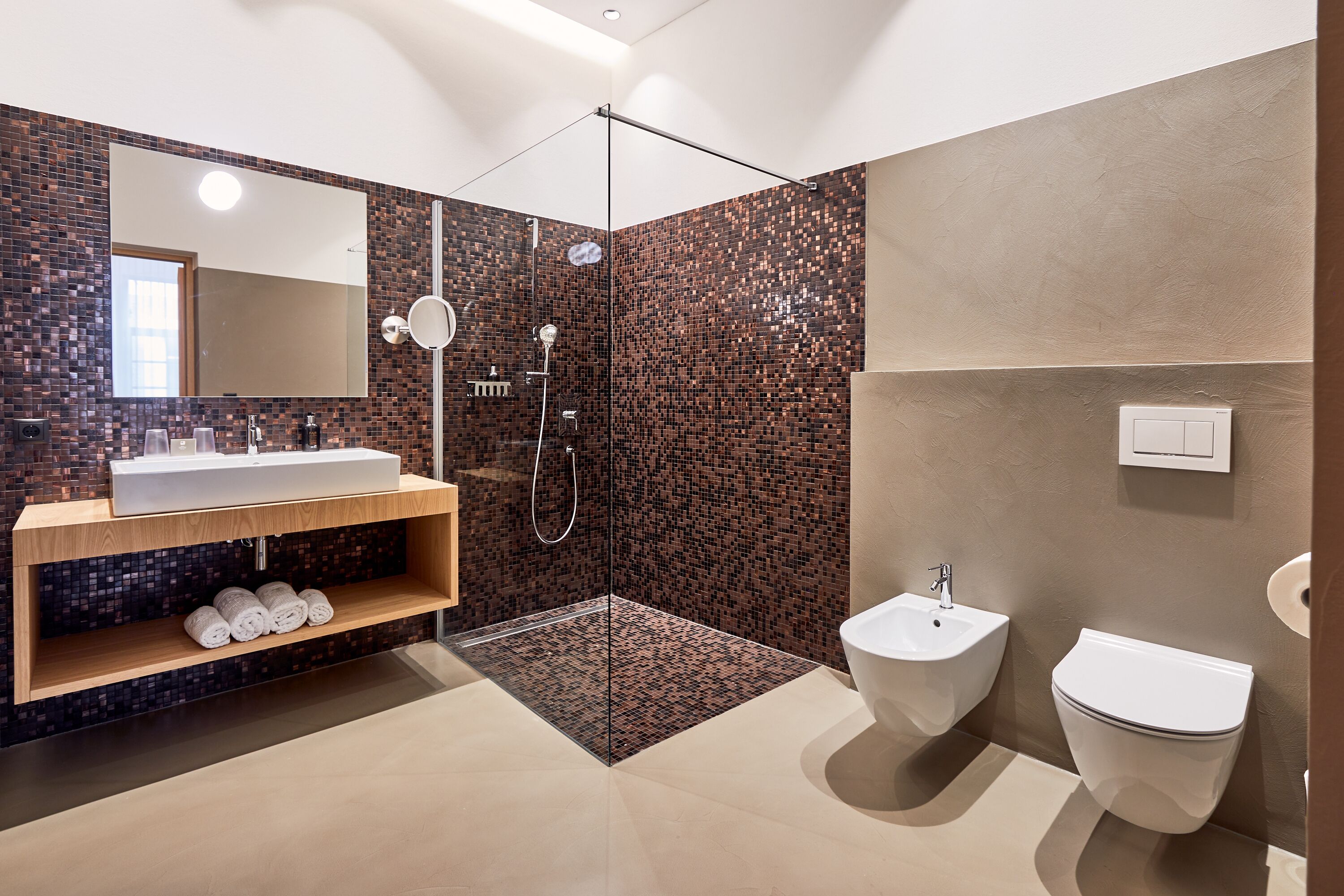 Un baño moderno con un espejo grande, un lavabo, un bidé y una ducha.