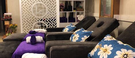 A spa area with massage tables, towels, and a decorative wall with a geometric pattern.