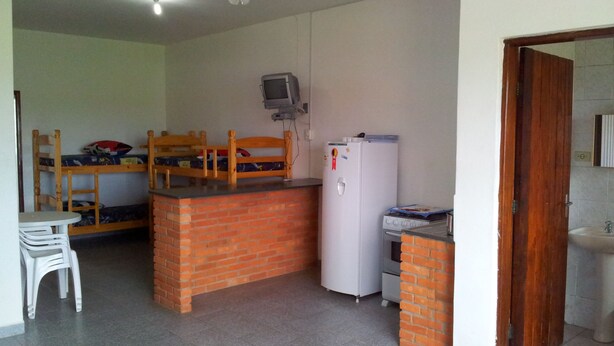 Cocina compacta con encimera de ladrillo, un refrigerador, un lavamanos y un banco de madera.