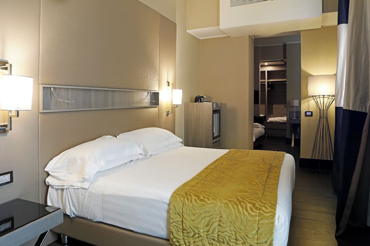 Ein Hotelzimmer mit Bett, Nachttisch, Lampe und Schrank.