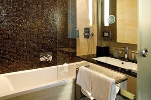 A modern bathroom with a glass-enclosed shower, a white bathtub, and a black countertop sink.