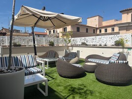 An outdoor seating area with wicker furniture, a white table, and a large umbrella.