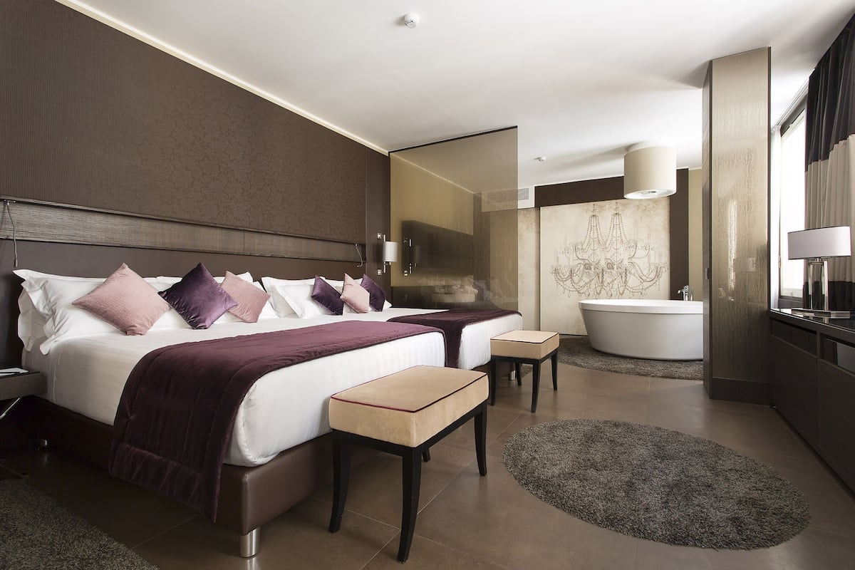 Ein modernes Hotelzimmer mit einem großen Bett, einem separaten Badezimmer und einer kleinen Sitzecke.